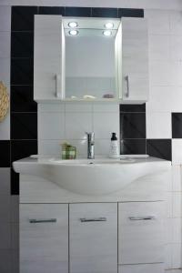 La salle de bains est pourvue d'un lavabo blanc et d'un miroir. dans l'établissement Villa Elizabeth Athos, à Ouranoupoli