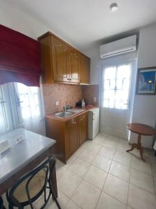 cocina con armarios de madera, fregadero y mesa en AEOLOS Apartments en Akrotiri