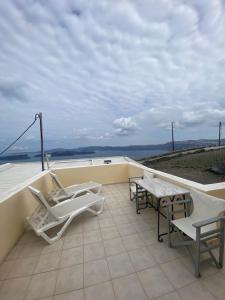 patio con sedie e tavoli sul tetto di AEOLOS Apartments ad Akrotírion