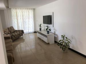 een woonkamer met een bank en een flatscreen-tv bij Casa Aruana in Aracaju