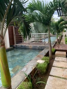 a pool with palm trees next to a building at Great family-friendly Appartment flic en flac MRU in Flic-en-Flac