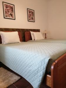 a bed with a blue comforter and two pillows at Casa Vaz 2 in Grândola