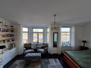 a bedroom with a bed and chairs and windows at 't Hanzehuys in Kampen