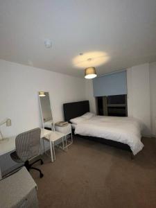 Zimmer mit 2 Betten, einem Schreibtisch und einem Stuhl in der Unterkunft Entire 2 bedroom flat in London