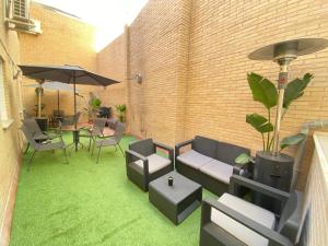 un patio con césped verde, sillas y sombrilla en Futurotel Space Spa Garden, en Granada