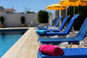 a group of blue chairs with umbrellas and a pool at Mira Parque in Albufeira
