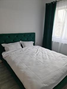 uma grande cama branca com uma cabeceira verde e uma janela em APARTAMENT IN CENTRU em Oradea