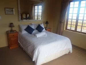 1 dormitorio con 1 cama blanca grande con almohadas azules en Witteklip self-catering farm, en Kleinmond