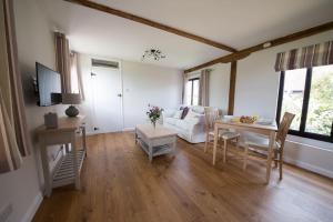 a living room with a table and a couch at Countryside cottage with pool in High Halden