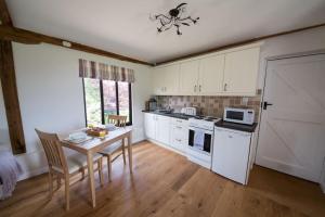 a kitchen with white cabinets and a table with chairs at Countryside cottage with pool in High Halden