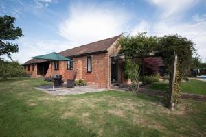 a brick house with a green umbrella in a yard at Countryside cottage with pool in High Halden