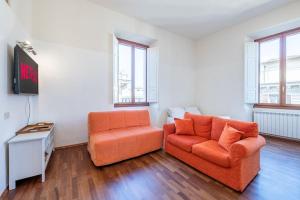 salon z pomarańczową kanapą i krzesłem w obiekcie [Duomo] Elegante Appartamento we Florencji