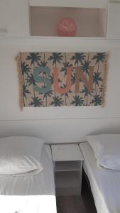 een slaapkamer met 2 bedden en een muur met palmbomen bij Mobil-Home 6 Personnes in Saint-Pair-sur-Mer