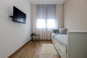 1 dormitorio con 1 cama, TV y ventana en North Views Luxury Apartment, en Subotica