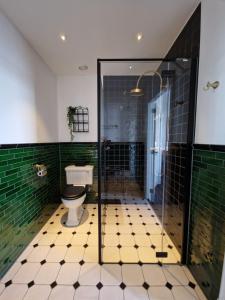 La salle de bains est pourvue de toilettes et de murs carrelés verts. dans l'établissement 't Hanzehuys, à Kampen