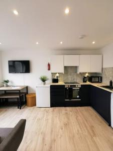 a kitchen with white cabinets and a wooden floor at Eastern Green Apartment, Penzance - Beach access and Parking in Penzance