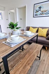 uma mesa de madeira com pratos e tigelas na sala de estar em Eastern Green Apartment, Penzance - Beach access and Parking em Penzance