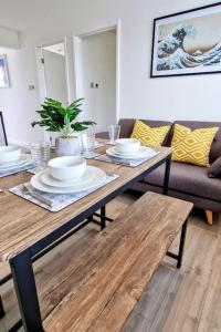 a wooden table with plates and bowls on it in a living room at Eastern Green Apartment, Penzance - Beach access and Parking in Penzance