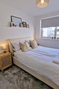 a white bedroom with a bed with a window at Eastern Green Apartment, Penzance - Beach access and Parking in Penzance +24 photos