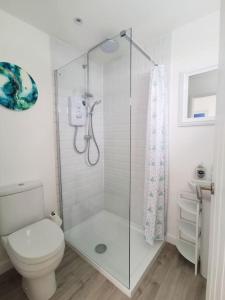 uma casa de banho branca com um chuveiro e um WC. em Eastern Green Apartment, Penzance - Beach access and Parking em Penzance