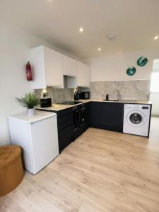 uma cozinha com armários brancos e uma máquina de lavar e secar roupa em Eastern Green Apartment, Penzance - Beach access and Parking em Penzance