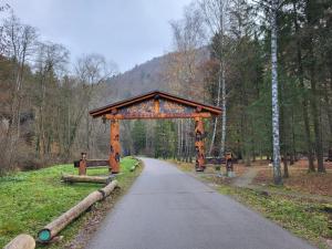 una carretera con un arco de madera en medio de un bosque en Blatnica Bee494 Apartment, en Blatnica