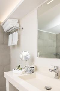 Un baño blanco con lavabo y espejo. en Sunrise Village Beach Hotel, en Kalamaki Messinia