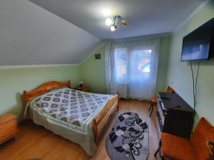 a bedroom with a bed and a television and a window at Casa Aurici Vatra Dornei in Vatra Dornei
