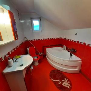 baño rojo con lavabo, bañera y aseo en Casa Aurici Vatra Dornei, en Vatra Dornei