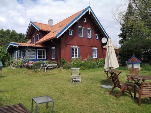 a red house with a table and chairs in front of it at Vecekrug Apartaments in Preila