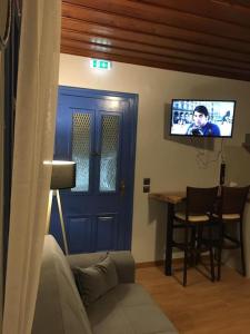 a living room with a blue door and a tv at Memory luxury studio The sibling apartments in Mytilinioí