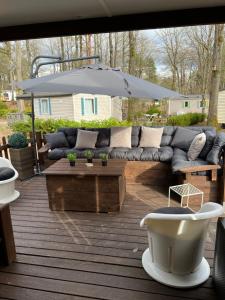 a patio with a couch and an umbrella at mobil home in Mirgaudon