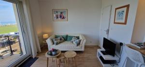 a living room with a white couch and a television at L'Albâtre in Dieppe