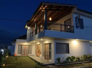 a white house with a balcony at night at Agusta Lake View Bedugul in Pabean Buleleng