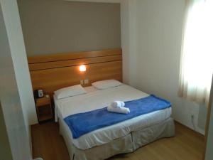 a bedroom with a bed with two towels on it at Wafeh Flats em San Diego Lourdes in Belo Horizonte