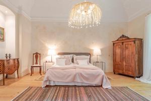 a bedroom with a large bed and a chandelier at Svastics kúria in Szentgáloskér