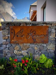 un letrero oxidado en una pared de piedra con flores en La Villa Kazuera en Cilaos