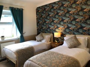 two beds in a hotel room with a wallpaper at Dalgreine Guest House in Blair Atholl