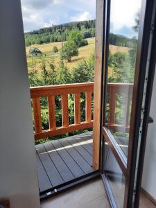 a door to a balcony with a view of a field at Agroturystyka Patynówka in Kletno