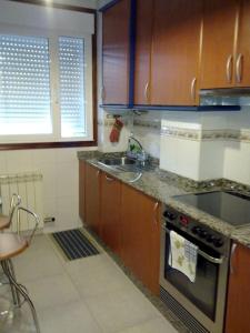 cocina con fregadero y fogones horno superior en Piso acogedor con Parking, en Vigo