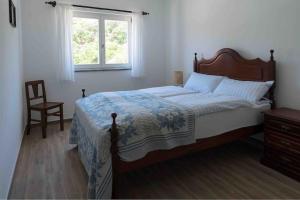 a bedroom with a bed and a chair and a window at Casa a pequena sereia in Benagil with sea view in Carvoeiro