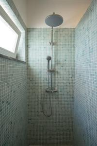 a shower in a bathroom with green tiled walls at Casa a pequena sereia in Benagil with sea view in Carvoeiro