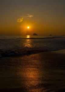 a sunset on the beach with the ocean at La Loma Linda: Bungalows, Yoga and Feldenkrais in Zipolite