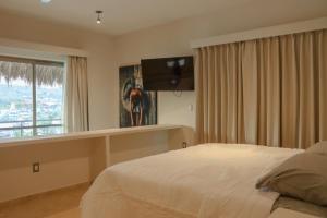 a bedroom with a bed and a flat screen tv at Hotel Casa Justina in Puerto Ángel