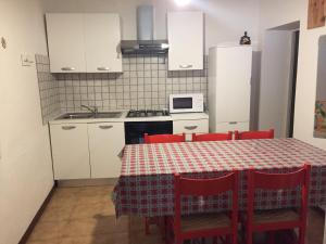 a kitchen with a table with red chairs and a microwave at Via Roma41 in Chiesa