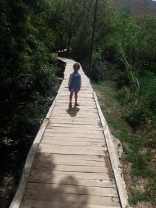 a little boy standing on a wooden walkway at Riad Les 5 Lunes in Aït Idaïr