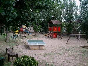 plac zabaw z kilkoma huśtawkami i stołem w piasku w obiekcie Appartement T2, terrasse, piscine, clim, proche plage w mieście Marseillan
