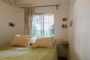 1 dormitorio con 1 cama con 2 almohadas y ventana en El apartamentito de Casa del Abuelo, en Isla Canela
