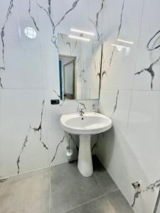 een witte badkamer met een wastafel en een spiegel bij Central room private entry and bathroom in Tirana
