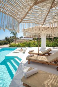 a resort with a swimming pool with chairs and umbrellas at Gatsby Rhodes-Brand New Seaview Villa in Asgourou